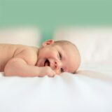 Ein Baby schaut lachend in die Kamera.