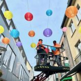 KSR-Elektriker Vasil Stojani und der Auszubildende Can Maurice Lutsch installieren an der Große Geldstraße in Recklinghausen die ersten bunten Lampions.