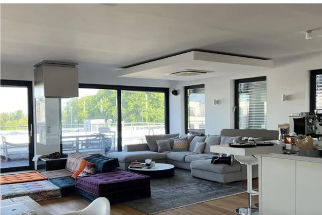 Wohnzimmer mit vielen gepolsterten Möbeln und ein Tresen mit einem höhenverstellbaren Stuhl.
