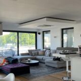 Wohnzimmer mit vielen gepolsterten Möbeln und ein Tresen mit einem höhenverstellbaren Stuhl.