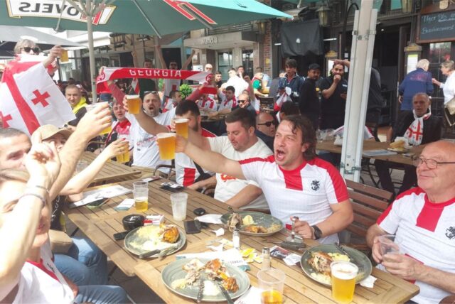 Georgische Fans trinken, essen und feiern am Alten Markt.