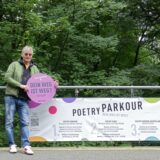 Künstler Markus Jöhring aus Recklinghausen lehnt an einem Plakat zu seinem Projekt „Poetry Parkour“ im Stadtgarten.