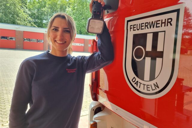 Eine Frau steht an einem Feuerwehrwagen.