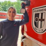 Eine Frau steht an einem Feuerwehrwagen.