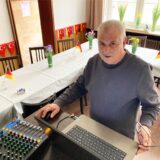 Wolfgang Hagemeier steht vor einem Tisch mit einem Laptop und einem Mischpult.