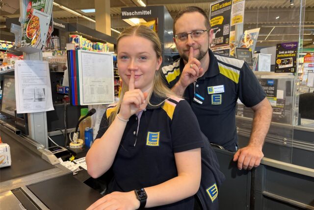 Ein junge Frau und ein Mann halten den Finger als Psst-Zeichen vor den Mund.