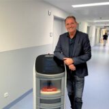 Pflegedirektor Frank Huismann aus Recklinghausen steht im Krankenhausflur des Prosper-Hospitals neben Roboter Jeeves.