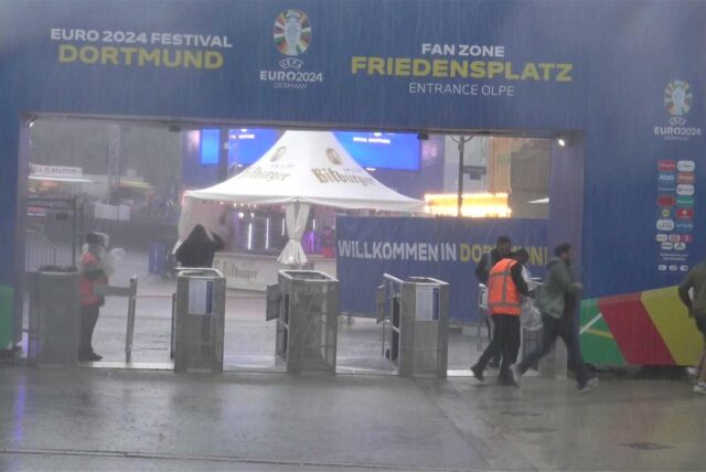 Am Eingang zum Public Viewing auf dem Friedensplatz suchen die Menschen das Trockene.