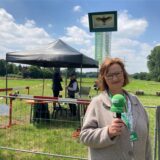 Eine Frau steht mit Mikrofon auf der Vogelwiese