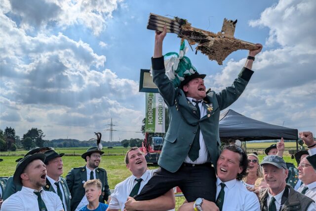 Ein Mann in Schützenrock wird von Schützenkameraden auf den Schultern getragen.
