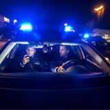 Zwei Polizisten in einem fahrenden Streifenwagen mit Blaulicht