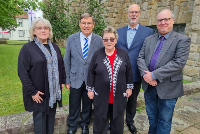 Fünf Personen stehen vor einer Kirche.