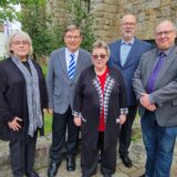 Fünf Personen stehen vor einer Kirche.