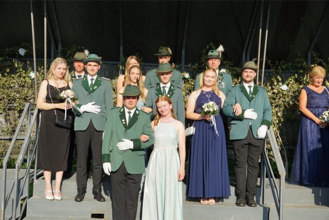 Männer in Schützenuniform und Frauen in Abendkleidern stehen auf einer Treppe.