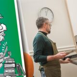 Mann schiebt Backblech in den Ofen.