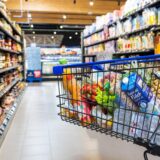 Ein gefüllter Einkaufswagen steht im Gang im Supermarkt.