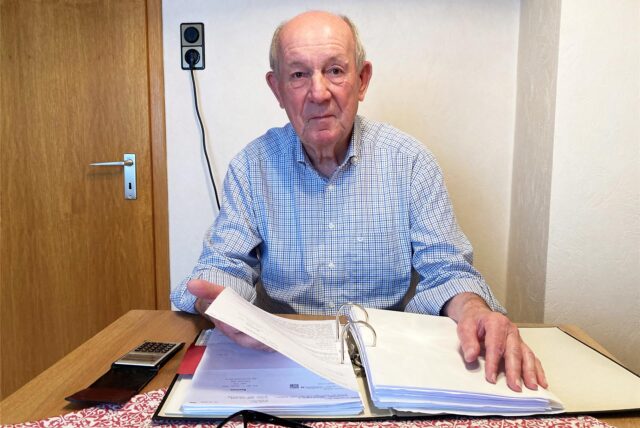 Werner Speith aus Herten-Westerholt sitzt an einem Tisch. Vor ihn liegt ein Aktenordner, in dem der 80-Jährige blättert.