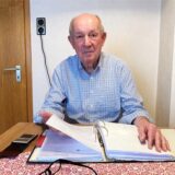 Werner Speith aus Herten-Westerholt sitzt an einem Tisch. Vor ihn liegt ein Aktenordner, in dem der 80-Jährige blättert.