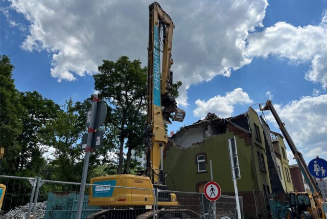 Ein großer Bagger steht vor einem Haus an der Römerstraße.