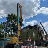 Ein großer Bagger steht vor einem Haus an der Römerstraße.