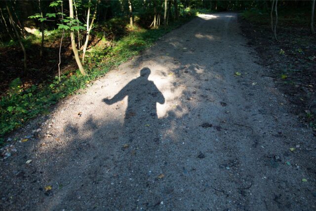 Schatten eines Mannes auf einem Waldweg