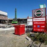 Überreste des Hagebaumarkts in Castrop-Rauxel, an dem ein grüner Bagger den Schrott aufsammelt.