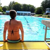 Eine Frau sitzt auf dem Rand des Schwimmerbeckens in der Mollbeck in Recklinghausen.