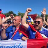 Französische Fußball-Fans rufen Fangesänge und halten die französische Flagge vor sich.