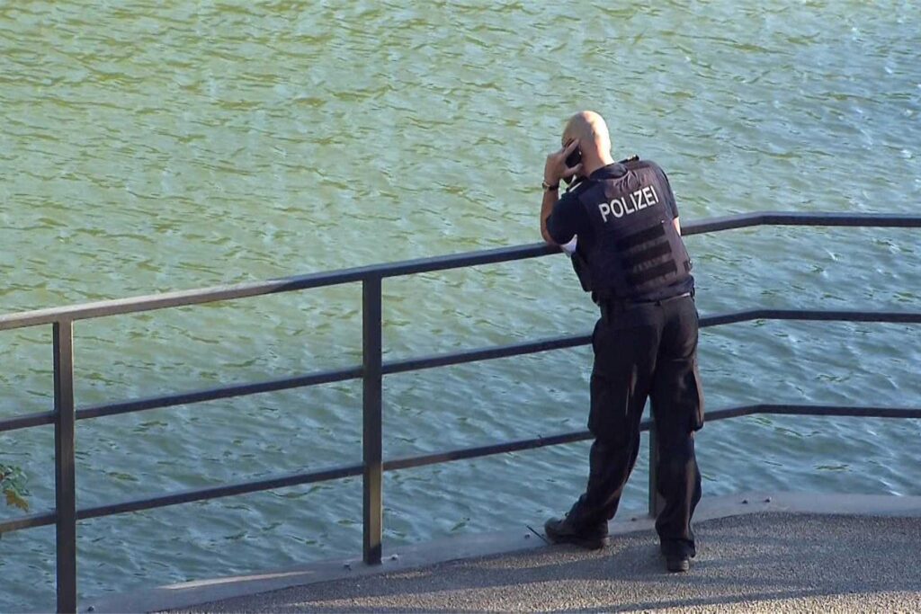 Ein Polizist steht an einem Geländer am Dortmund-Ems-Kanal und telefoniert. Ein Polizist steht an einem Geländer am Dortmund-Ems-Kanal und telefoniert.