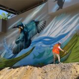 Max Packheiser sprüht den Background für den Eisvogel am Fundament der neuen Stahlbrücke am Vater-unser-Weg.