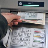 Eine Hand greift nach Geld aus einem Geldautomaten