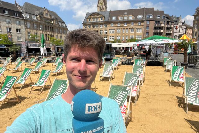 Jan Weffers steht am Marktplatz in Castrop-Rauxel vor einem aufgeschichteten Strand mit Liegestühlen.