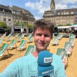 Jan Weffers steht am Marktplatz in Castrop-Rauxel vor einem aufgeschichteten Strand mit Liegestühlen.