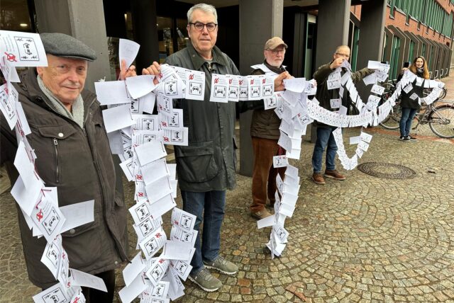 Menschen mit Zetteln stehen vor dem Rathaus.