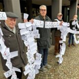 Menschen mit Zetteln stehen vor dem Rathaus.