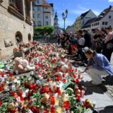 Menschen stehen am Rande eines Gottesdienstes für die getötete Valeriia in Döbeln vor Blumen und Kerzen.
