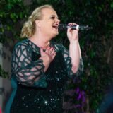 Die Hertener Musical-Darstellerin Meike Pöther steht auf einer Bühne und hält ein Mikrofon in ihrer linken Hand.