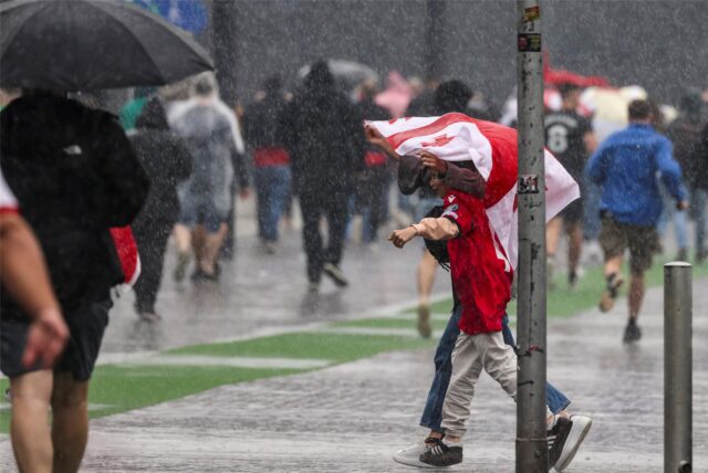 Fußball-Fans gehen durch den Regen.