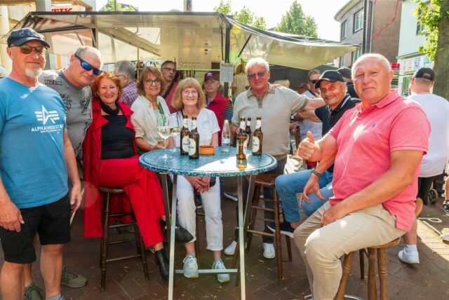 Eine Gruppe von Männern und Frauen sitzen auf dem Feierabendmarkt in Herten-Langenbochum um einen Tisch herum.