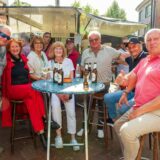 Eine Gruppe von Männern und Frauen sitzen auf dem Feierabendmarkt in Herten-Langenbochum um einen Tisch herum.