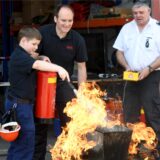 Ein Mitglied der Westerholter Jugendfeuerwehr bekämpft mit einem Erwachsenen Flammen mit einem Feuerlöscher.
