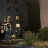 Zwei Spezialeinsatzkräfte tragen in Schutzanzügen und unter Atemschutz eine Kiste aus einem Gebäude an der Hochstraße.
