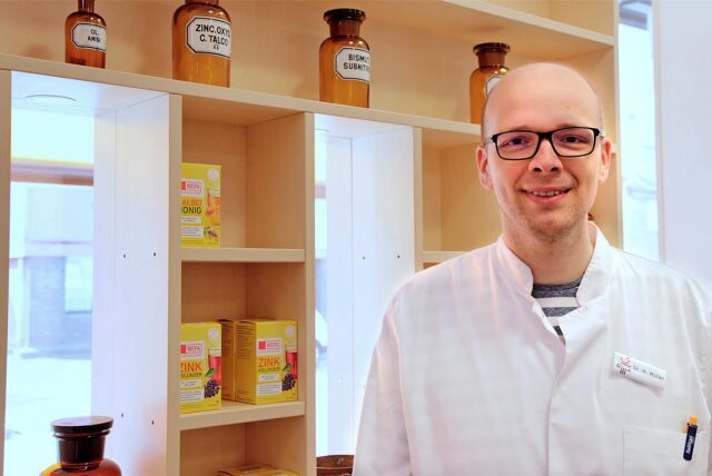 Ein Apotheker steht vor Medikamenten.