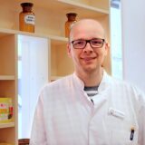 Ein Apotheker steht vor Medikamenten.