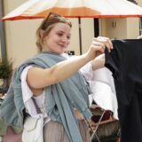 Eine junge Frau stöbert Kleidungsstücke auf einem Flohmarkt in Dortmund durch.