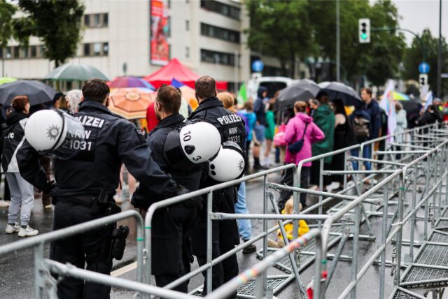 Drei Polizisten beobachten etwa 150 Demonstranten hinter einer Absperrung an der Grugahalle in der der AfD-Bundesparteitag fortgesetzt wird.