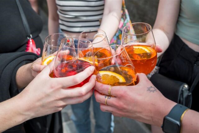 Fünf Personen stoßen mit Aperol Spritz in Gläsern an. (Symbolbild)