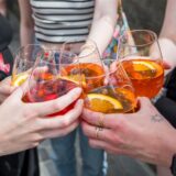 Fünf Personen stoßen mit Aperol Spritz in Gläsern an. (Symbolbild)