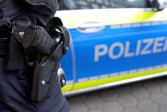 Ein Polizist steht vor einem Einsatzfahrzeug der Polizei.