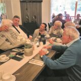Menschen sitzen an einem Tisch und schauen in eine Zeitung.